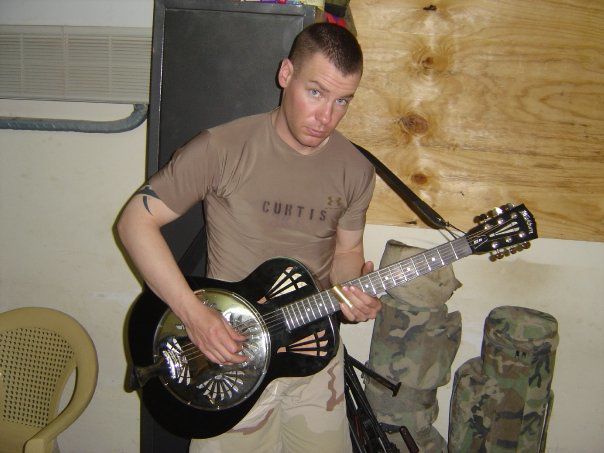 Jake Curtis playing guitar in Iraq